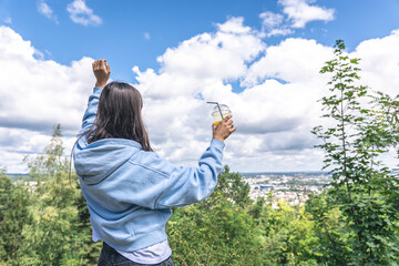 A young woman drinking juice from a straw in the park.