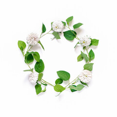 Obraz premium The wreath is made of white aster flowers and branches with green leaves. A simple floral arrangement on a white background. Flat lay, top view, copy space.