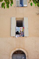 Fototapeta na wymiar Laundry drying on the window of a bright yellow house in an old mediterranean town