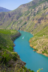 View of a distant boat sailing along the famous amazing Sulak Canyon in the Caucasus mountains in the Republic of Dagestan, Russia. Selective focus