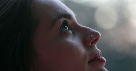 Young woman face opening and closing eyes. Girl meditating and in contemplation looking up to the...