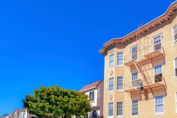 Fototapeta premium Aparment building with painted lined stucco wall and emergency ladder along with the suburbs houses