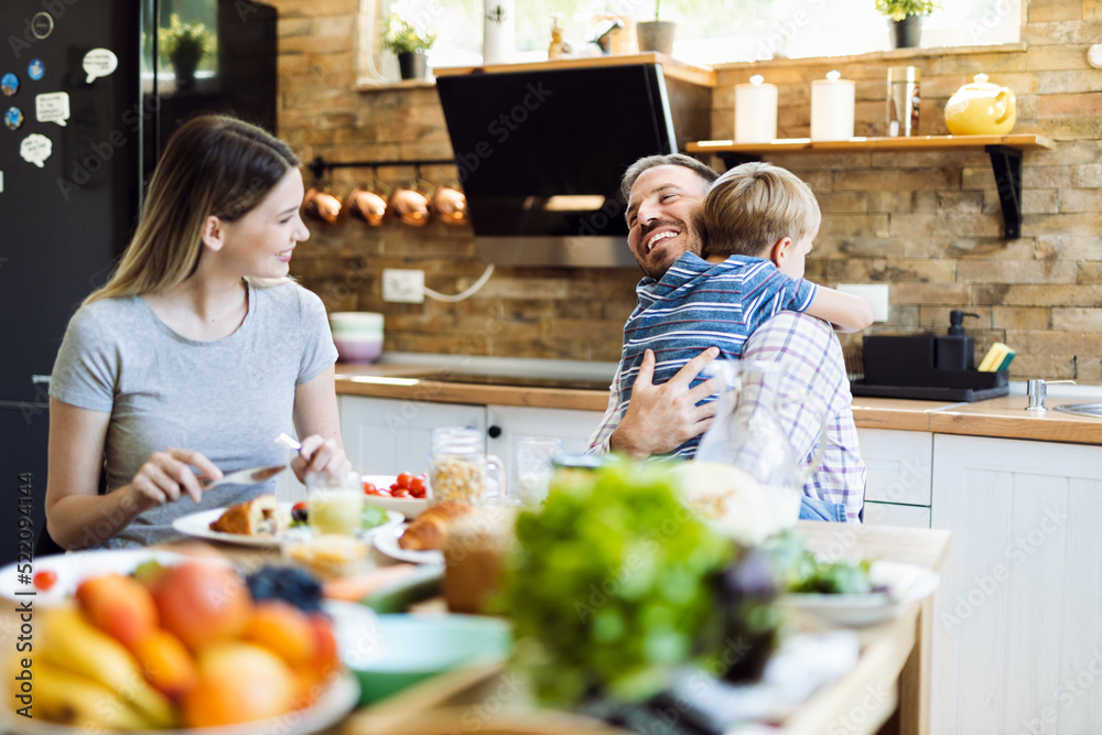 Wall mural young happy family enjoying in their breakfast time in dining room