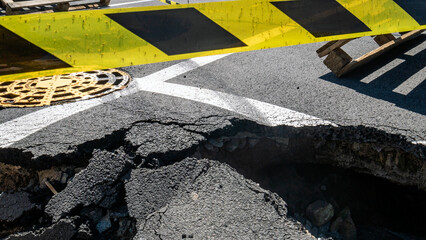 Dangerous stretch of road with damaged asphalt. The accident site is fenced off with black and...