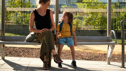 Mother and small toddler are waiting for the bus at the bus stop