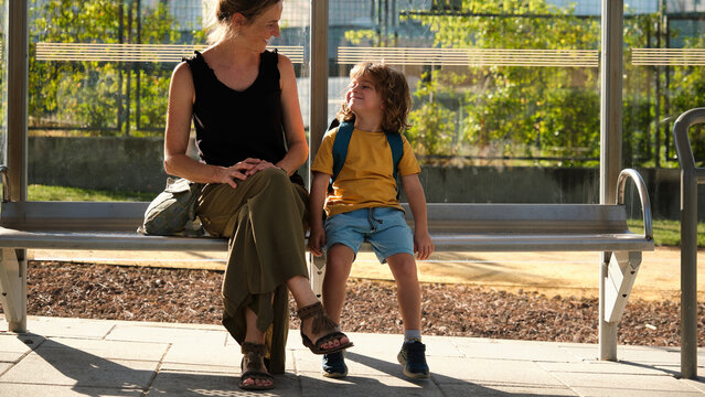 Mother And Small Toddler Are Waiting For The Bus At The Bus Stop