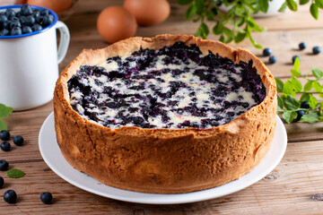 Pie with fresh and cooked blueberries on wooden table