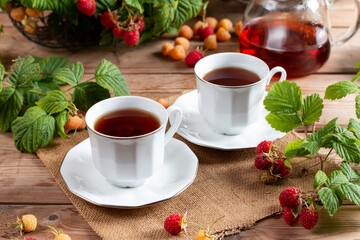 Flavored raspberry tea. Vitamin hot steaming drink with natural berries on wooden table