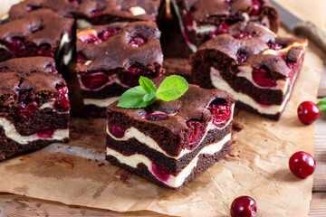 Chocolate brownie pieces decorated with cherry on wooden table
