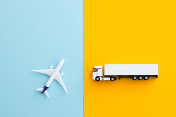 Miniature toy airplane and truck on color background. Trip by airplane.