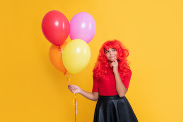 pondering teen girl with party balloon on yellow background