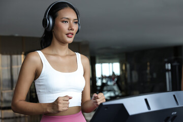 Beautiful attractive woman listening music and exercise on treadmill machine in gym fitness, urban...
