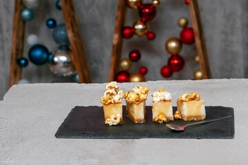 cheesecake with salted caramel and popcorn on a black slate board with a spoon in the middle of the...