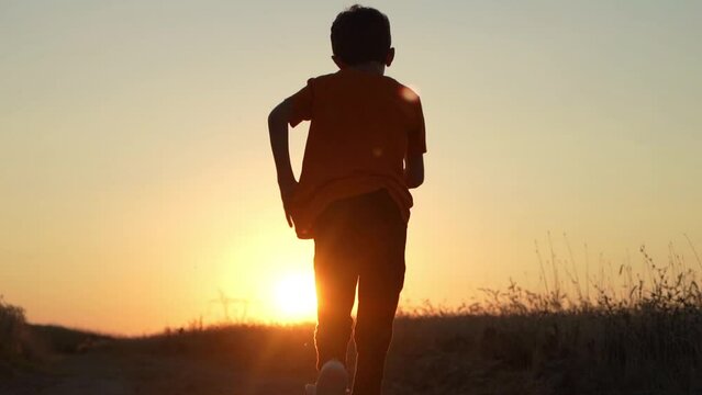 Boy running in nature at sunset, slow motion.