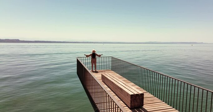 aerial view of Carefree woman looking at lake view outdoors standing on modern bridge