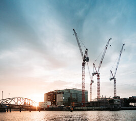 Fototapeta na wymiar construction cranes in the evening light at the water