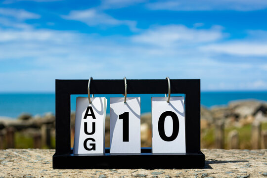 Aug 10 calendar date text on wooden frame with blurred background of ocean.