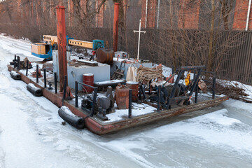 Small floating crane and service boat on a winter river
