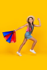 happy teen girl with shopping bags on yellow background. full length. childhood