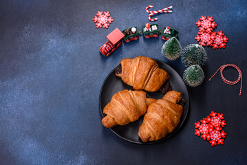 Crispy chocolate croissant with Christmas decorations on wooden cutting board