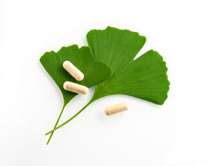 Two Ginkgo green leaves with pills for brain, memory protect therapy and treatment of dementia, isolated on white. Ginkgo Biloba composition - natural ingredient for alternative medicine, closeup. - 522102311