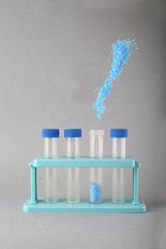 blue powder pouring into test tube against gray background