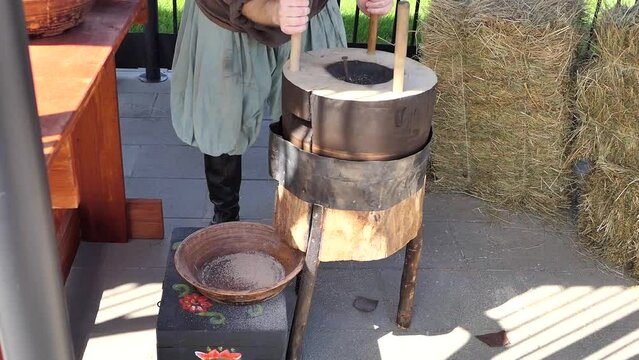  Antique wooden millstones for grain. A man grinds grain in millstones to make flour. High quality FullHD footage