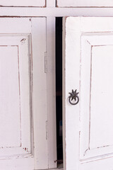 Ajar closet door. White freshly painted antique cupboard with half opened door.