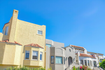 Facade of houses with painted stucco walls and clay tile roofs in San Francisco, CA