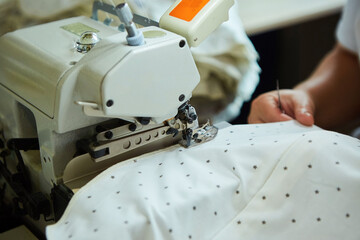 Industrial sewing production or atelier. The hands of tailors sewing fabrics on sewing machines to create clothes.