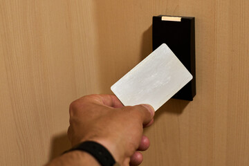Hand approaching a card to an rfid reader to open a security door