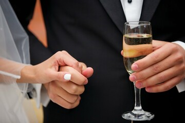 A glass of alcoholic beverage in the hands of an adult.