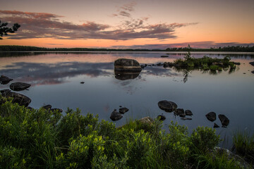 Fototapeta na wymiar Spectacular view at sunset over a lake, with rocks in the foreground, in the south of Sweden