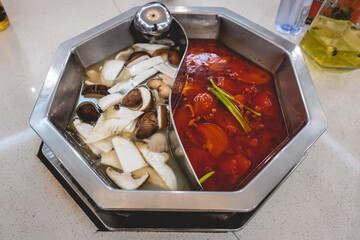 Traditional chinese yin yang double soup with mushrooms soup and tomato soup in a metal bowl