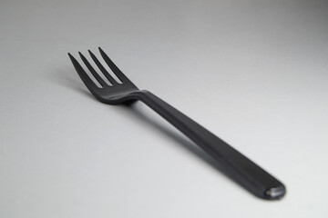 Black disposable plastic fork close-up. Disposable dishes. Soft focus