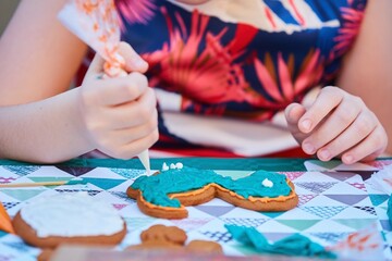 A teenager's hand is decorating a gingerbread. Delicious and creative activity for children and adults.