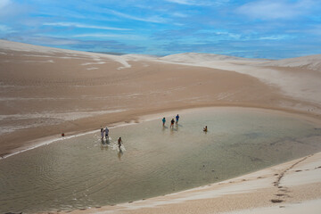 Fototapeta na wymiar Lençóis Maranhenses, MA, Brazil - March 12th, 2017 - People walking in the desert dunes with water