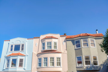 Fototapeta premium Three adjacent houses with clay roof tiles against the blue sky at San Francisco, California