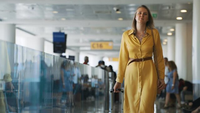 Woman with suitcase walking in airport terminal.
