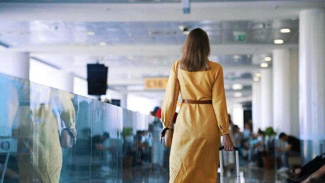 Woman walking in airport terminal. Back view.