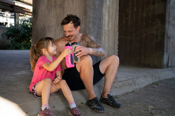 A father and his daughter having fun relaxing after workout.