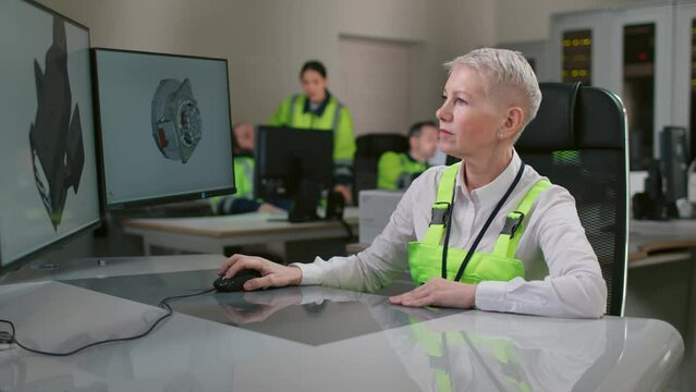 Mature woman engineer working on desktop computer in cad software with 3d component. 