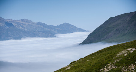 mountain plateau and valley with cloud filling the valley below and clear blue summer sky