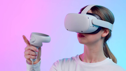 Close up of young woman in vr goggle moving hand with controller isolated over neon background