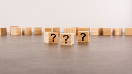 cube with question mark on wooden background. space for text