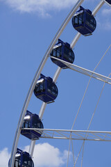 Amusement park. Attraction under the sky. Blue sky, clouds. Way up. Cabins in the sky. Fun, warm, summer time. Ferris wheel. Joy for children and adults. Fear and excitement