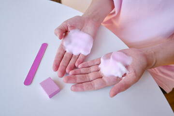 Manicure of female hands with soft soap or airy hand cream on a light background.
Cosmetic care for hands and nails. Beauty and health