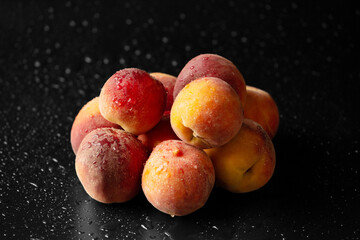 Fresh ripe juicy whole and cut red peaches on rough black background.
