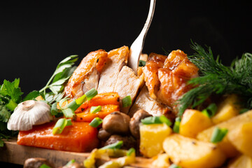Baked poultry and vegetables on a dark background