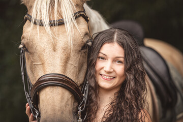 Portrait of a young woman and her stunning palomino kinsky horse. Female equestrian and her horse
